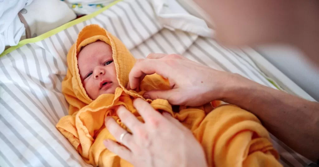 A Father Drying a Newborn Baby with a Towel after Bath at Home